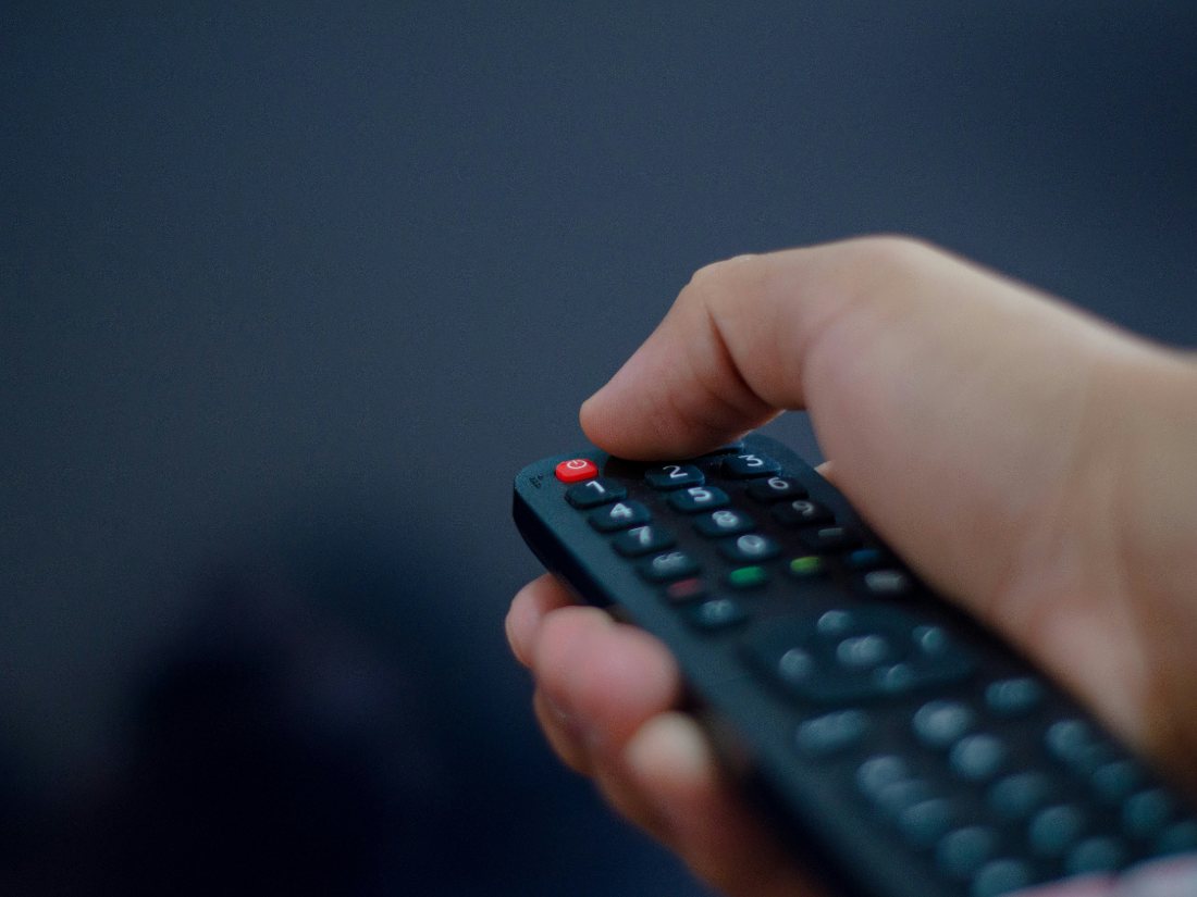 A hand holding a TV remote, ready to switch on SastaTV